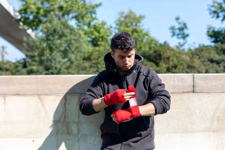 Boxer preparing for training with forearm bandage outdoors