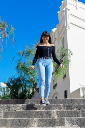 Young stylish woman wearing earphones spending free time outdoors standing listening to music looking awayの写真素材