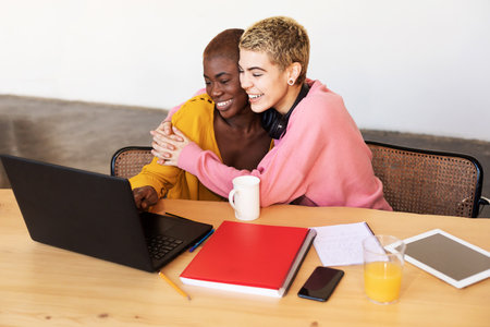 Lesbian couple with laptop on table at homeの写真素材