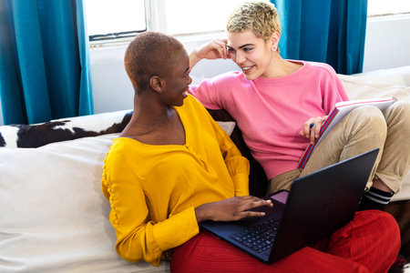 Beautiful lesbian couple with a laptop resting at homeの写真素材