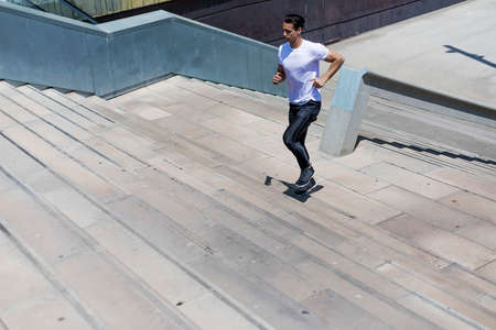 Young sport man running upstairs on city stairs