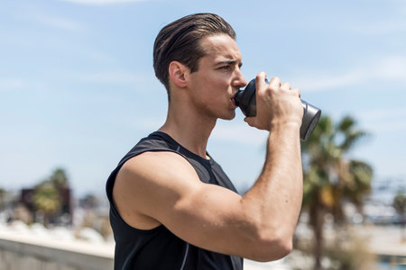 Young Man Drinking Water After Running. Portrait.