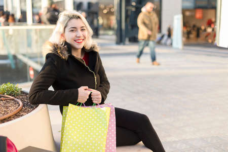 A smiling shopper sitting on a street benchの写真素材