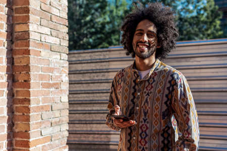 Portrait of handsome afro man using his mobile in the street.の写真素材