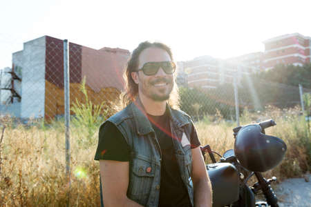 Young male wearing sunglasses on a chopper motorcycle looking at cameraの写真素材