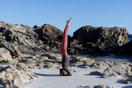 Young woman practice balance asanas on Summer yoga session on a beautiful beach at Formentera,...