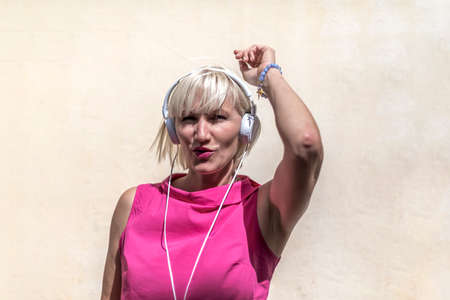 Funny Woman listening music and dancing on the streetの写真素材