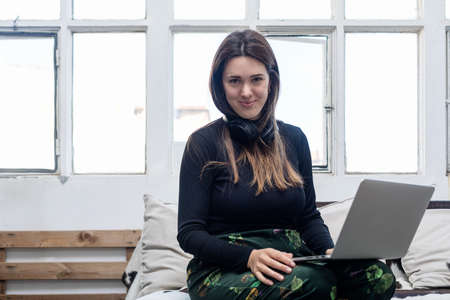 Curvy Woman sitting on sofa and using laptop.の写真素材