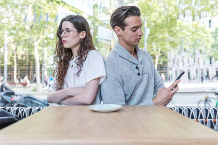 Young girl is feeling bored with her boyfriend because his addicted cellphone behavior ignoring her...