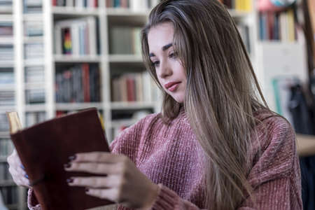 Relaxed young woman reading a book on a sofa at homeの写真素材
