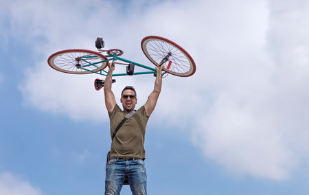 Urban man holding his bike wearing sunglassesの写真素材