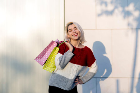 Portrait of young happy smiling woman standing against white wall smiling and looking to camera...