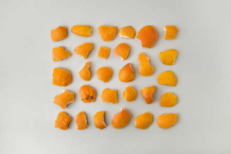 Neatly arranged pattern made with peel orange fruit on sandy colored background. Minimal flat lay.の写真素材