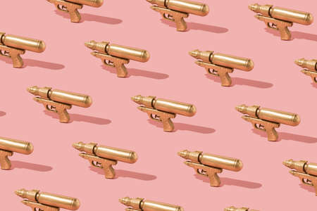 Trendy sunlight summer pattern made with golden water plastic gun on powder pink background. Minimal...
