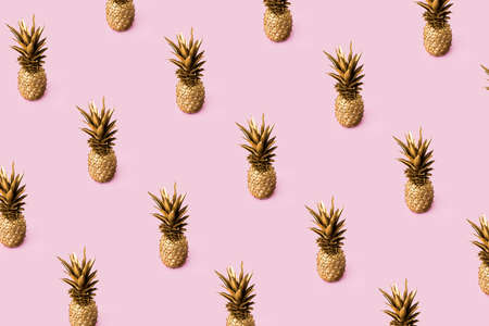 Trendy colorful fruit pattern of golden fresh pineapples on pink background. Minimal bold summer concept. Top view.の写真素材