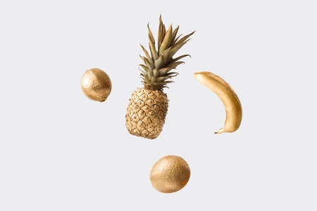 Creative sunlight summer arrangement with golden flying fresh fruits against grey background. Minimal nature concept. Copy space.の写真素材