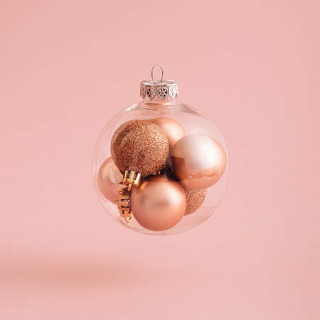 Flying or levitate Christmas ball with xmas baubles inside with sunny day shadow. Creative idea on pink powder background. Minimal New Year transparent concept with place for text or banner.の写真素材