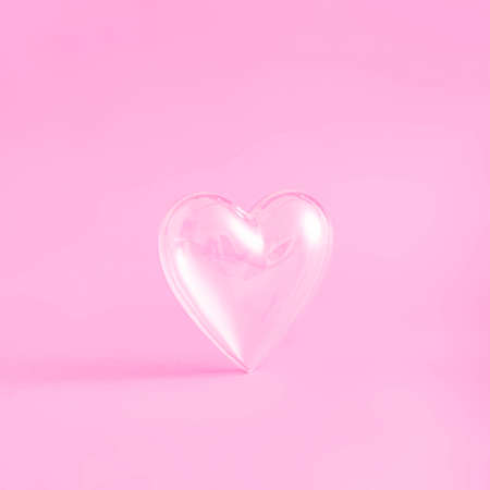 Creative love composition with transparent heart glass on colorful pink background. Minimal...