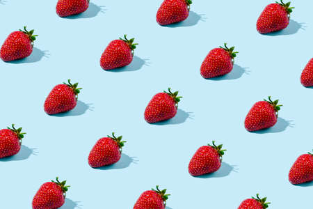 Sunlight summer pattern made with strawberries fruit on bright blue background. Minimal trendy food...