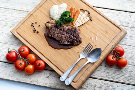 Grilled beef put on wooden chopping board with vegetable.の写真素材