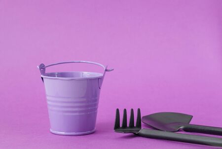 Toy bucket light purple, rake and shovel on a dark purple background.の写真素材