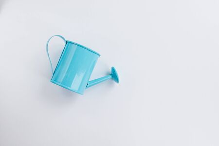 Blue watering can toy on a white background. Place for text. The concept of agriculture. View from top.の写真素材