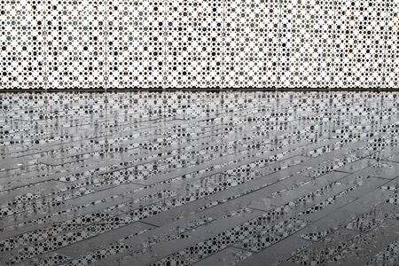 Background. Perforated white wall and its reflection on the wet tile after the rain.の写真素材