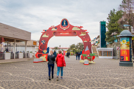 Sochi, Russia, February 8, 2019. Two unidentified girls are coming to the Central waterfront. The entrance is decorated with gates with symbols of the World Cup, which took place in the city in 2018.のeditorial素材