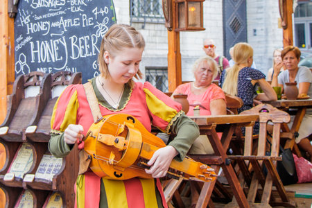 Tallinn Estonia 25 July 2018. On the street of the old town of Tallinn girl in a national costume adjusts folk instrumentのeditorial素材