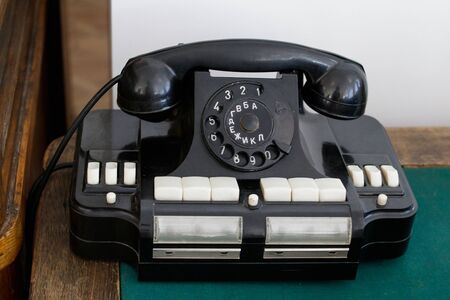 Old Soviet office phone with Russian letters on a wooden table, the tabletop is covered with green fabric.の写真素材
