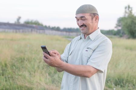 Muslim senior man uses a mobile phone in a Siberian villageの写真素材