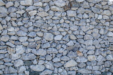A dense wall of gray-white small cobblestones. Textureの写真素材