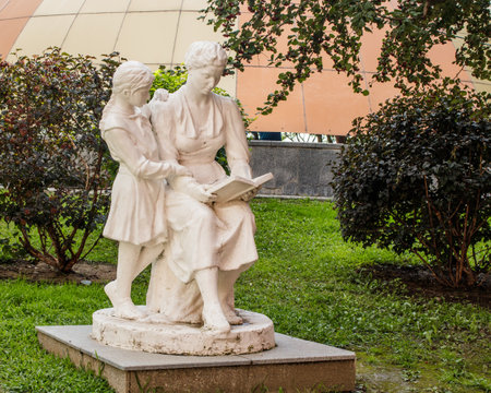 Massive traditional urban park gypsum sculpture of the times of the USSR. Mother reads a book to her daughter.のeditorial素材