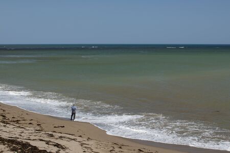 A fisherman fishing with a fishing rod on the coast of the Seaの写真素材