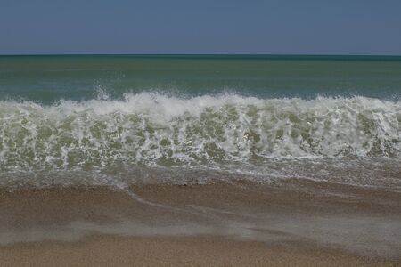 Sea wave running onto a sandy beach with foam and spray. Backgroundの写真素材