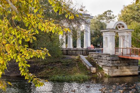 Old park in the fall. View through the branches of a white rotunda and an arch.の写真素材