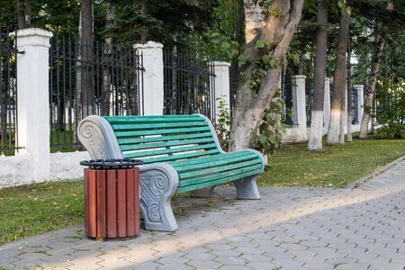 Wooden cozy green bench in the autumn city park.の写真素材