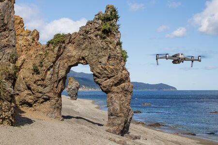 Beautiful stone natural arch, rock formation on the coast of the Sea of Okhotsk. The drone is out of focus. Cape Velikan, Sakhalin Island, Russia.の写真素材