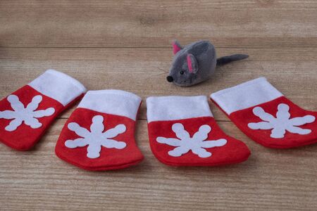 Composition of 4 toy red with snowflake boots for Christmas gifts and one rat on wood background.の写真素材