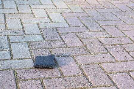 The lost black wallet lies on a light paving slab.の写真素材
