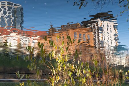 Autumn city landscape. Reflection of old and modern buildings in the water. Motion blur.の写真素材