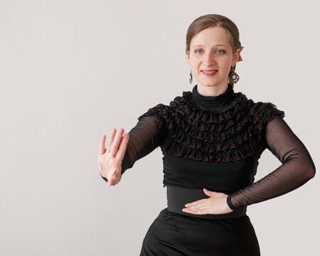 Beautiful young woman dancing flamenco in a black dress on a white background and smiling. Half-length portrait. Copy space. Place for text.の写真素材