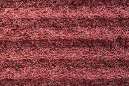 A close up of knitted woolen texture of coral color. Hand made. Top view.の写真素材