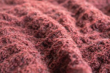 A close up of knitted soft woolen texture of coral color. Hand made.の写真素材