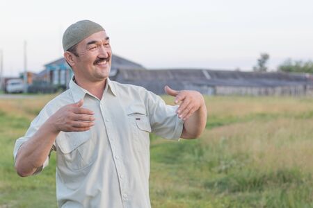Muslim senior man stands and smiles on the background of the Siberian village, Russiaの写真素材