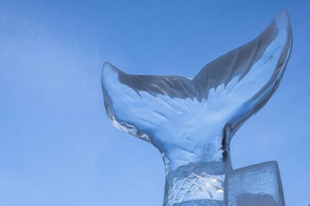An ice sculpture of a tail of fish against a blue sky background. Copy spaceの写真素材