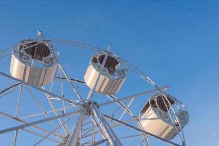 Part of a ferris wheel with round cabins decorated with ornaments against a blue sky. Copy space.の写真素材