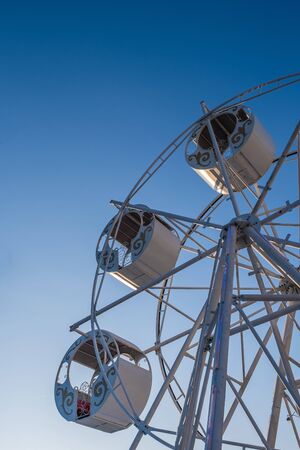 Part of a ferris wheel with round cabins decorated with ornaments against a blue sky. Copy space. Vertical photo.の写真素材