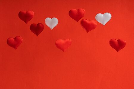 Valentines day card. 2 white and 7 red flying small textile hearts are on a background of red velvet paper. love wedding concept. Copy space place for textの写真素材