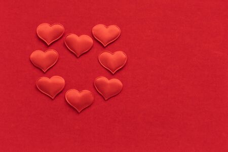 Valentines day card flat lay top view. 8 small textile red hearts are in the shape of a large heart...
